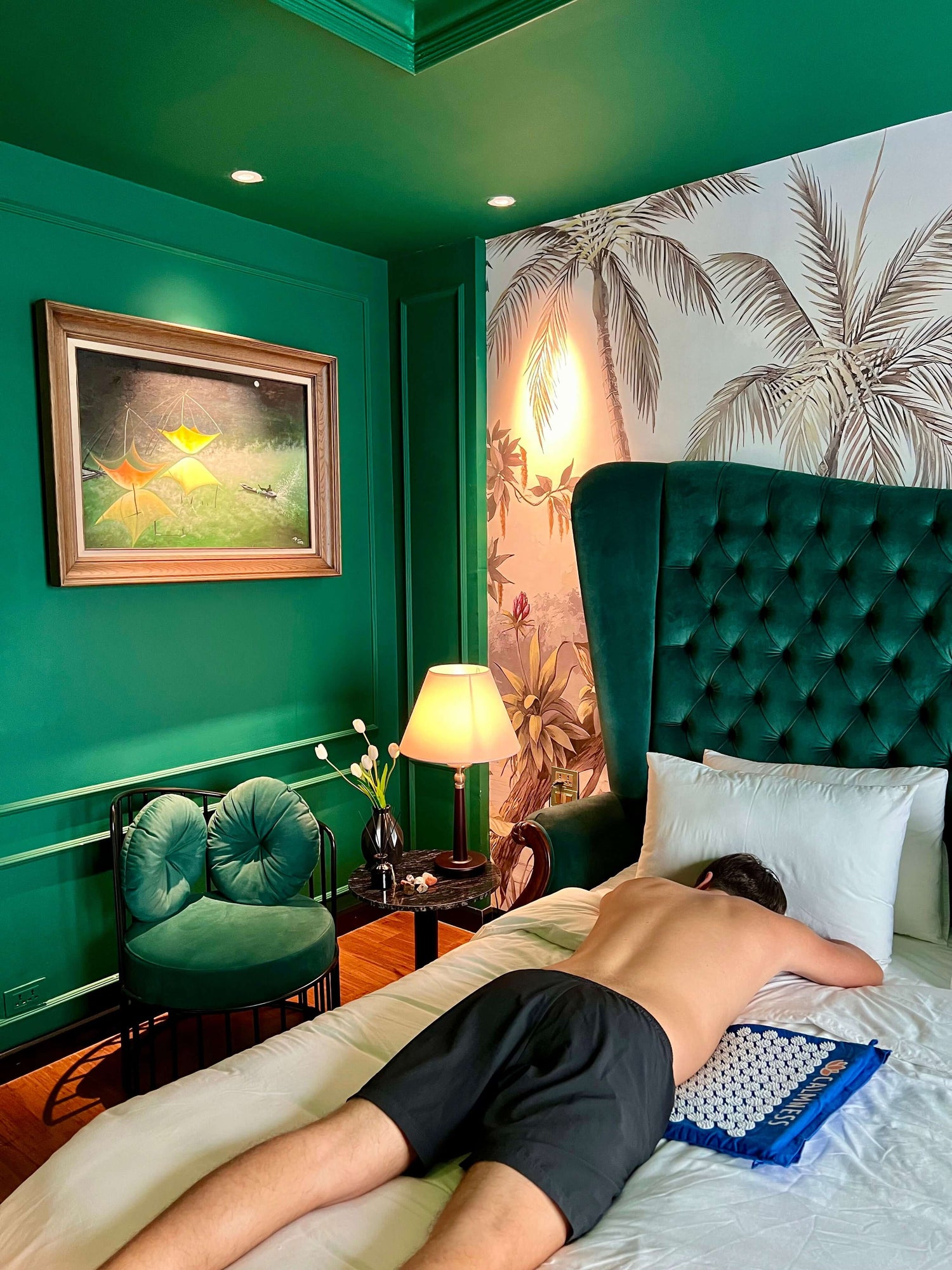 Man laying on his belly on the Calmness Acupressure Mat on a bed, promoting muscle relief and relaxation